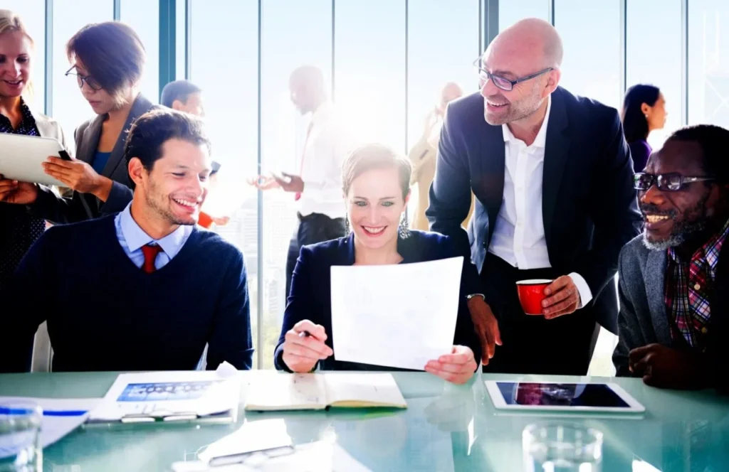 Smiling coworkers reviewing document during office meeting