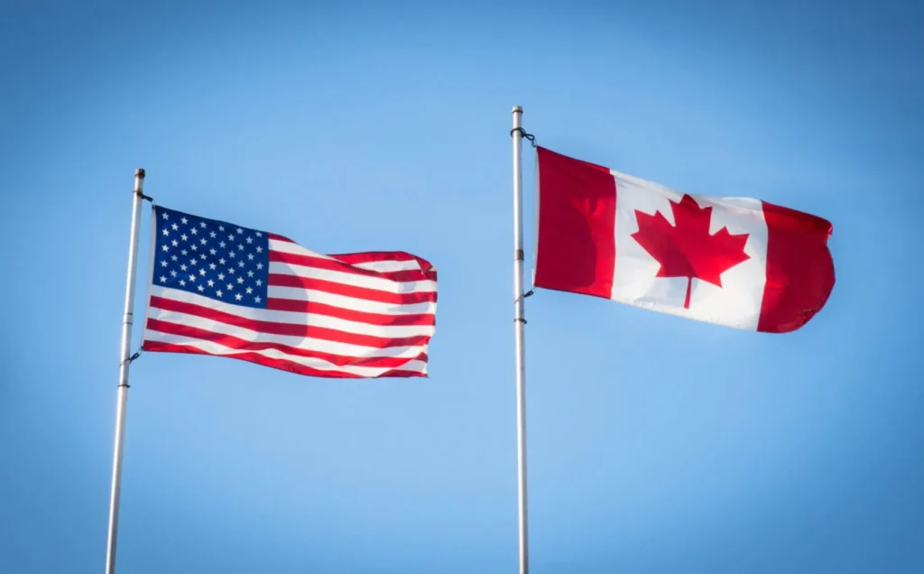 United States and Canada flags against blue sky