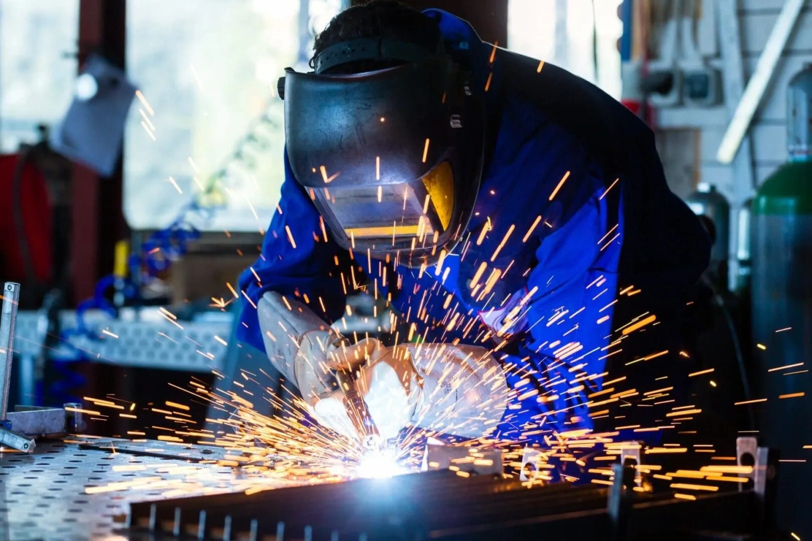 Welder welding metal with sparks in workshop