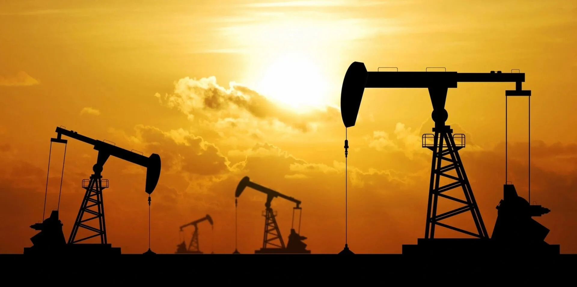 Oil pumpjacks silhouetted against orange sunset