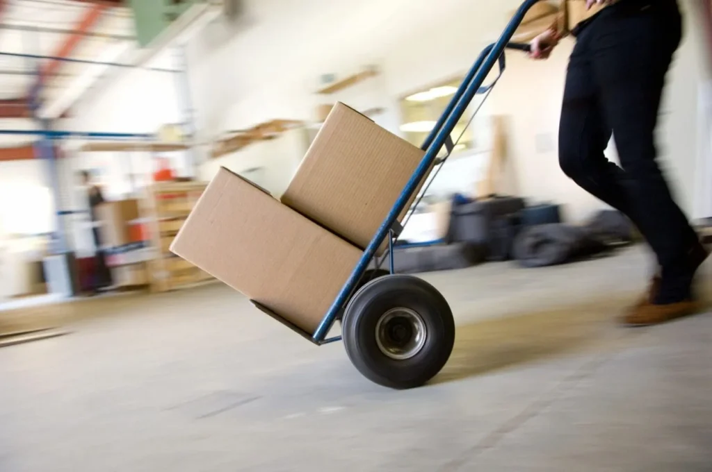 Warehouse worker pushing hand truck with boxes