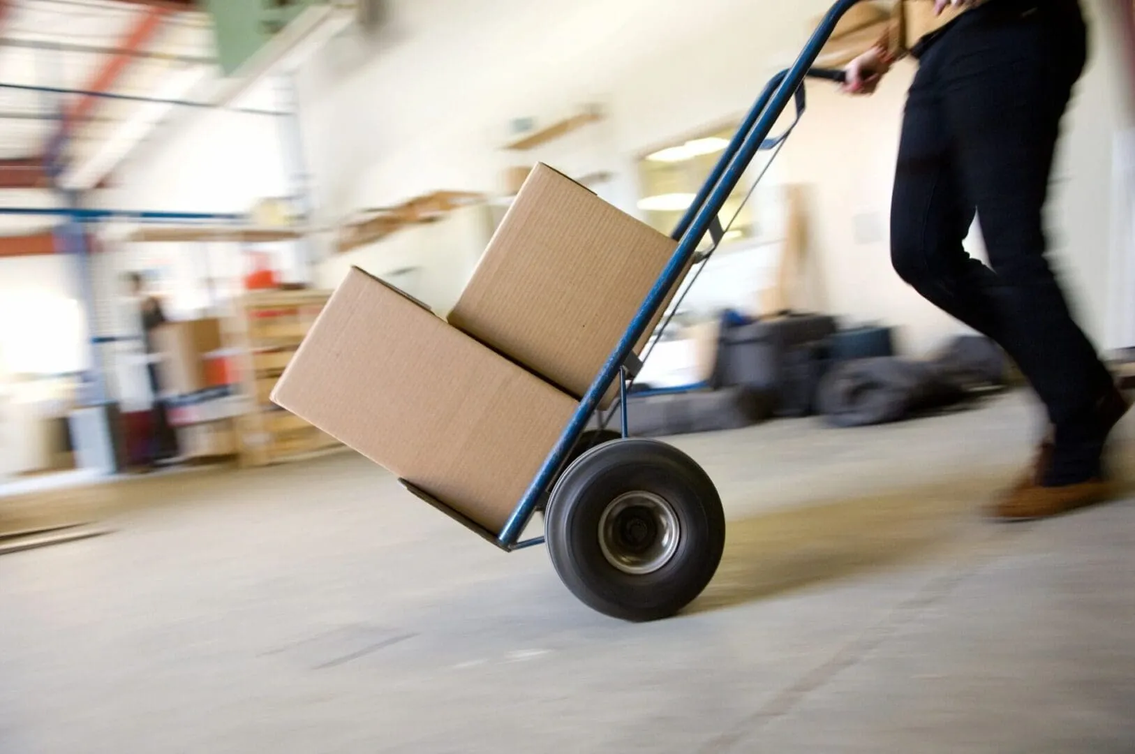 Warehouse worker pushing hand truck with boxes